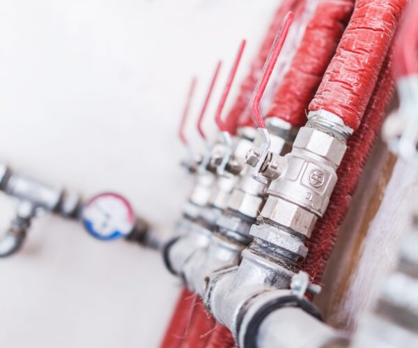 Home Plumbing System Closeup Photo. Red Isolated Pipes with Ball Valves. Residential Water Supply System.